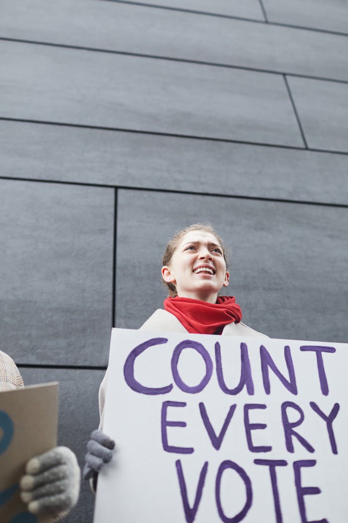 Smiling woman at a protest holding a 'Count Every Vote' sign, symbolizing democracy.