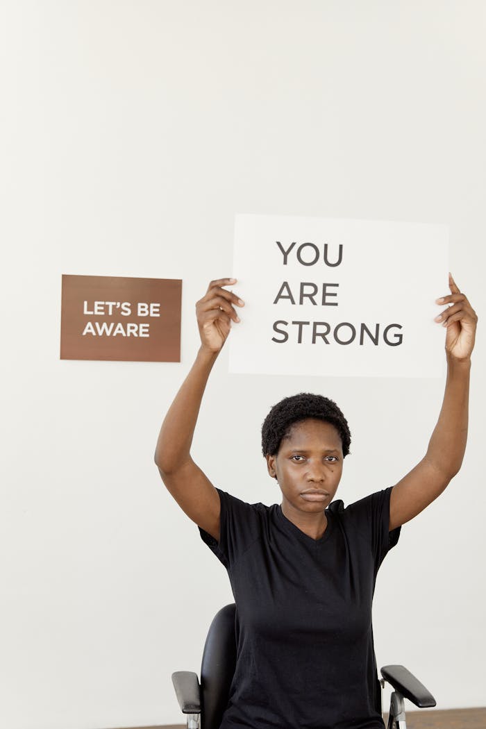 African American woman holding positive message signs for strength and awareness.